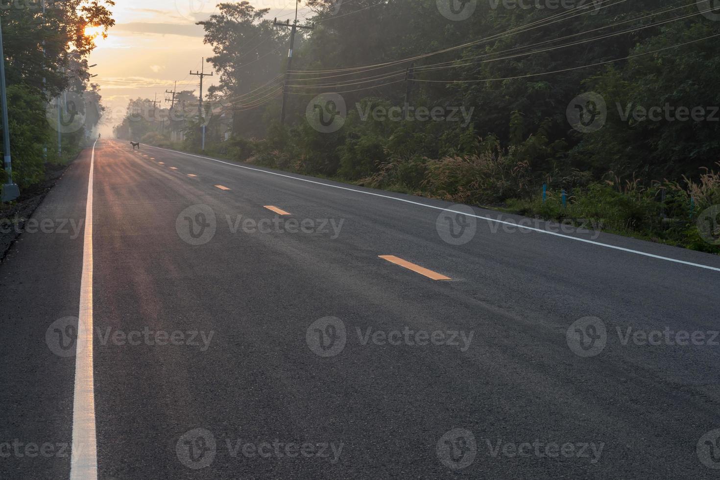 asfalterad väg med solen som går upp på landsbygden. foto