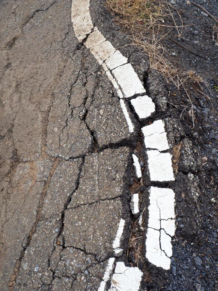 sprucken asfalt med vita linjer foto