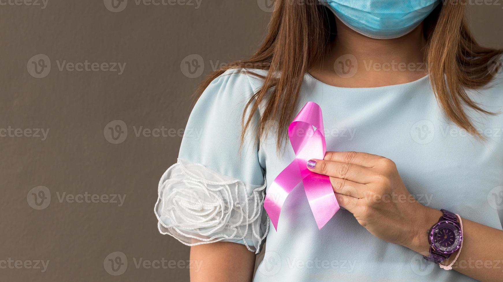 nära hand kvinna bär en mask som en symbol mot bröstcancer. foto
