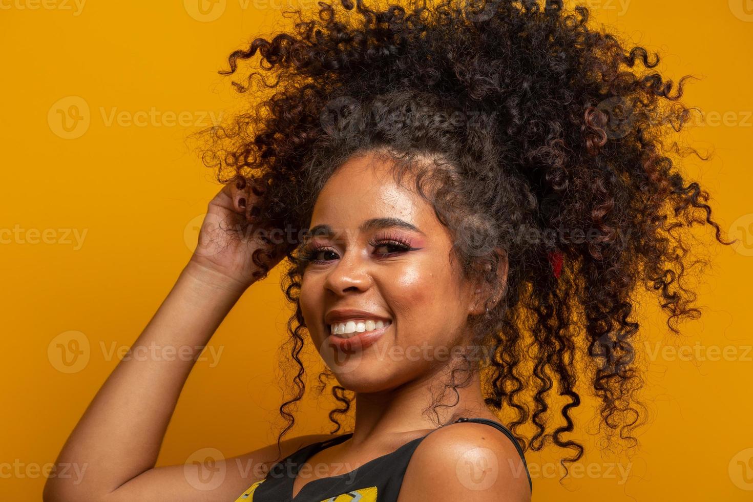 skönhet porträtt av afrikansk amerikansk kvinna med afro frisyr och glamour makeup. brasiliansk kvinna. blandras. lockigt hår. frisyr. gul bakgrund. foto