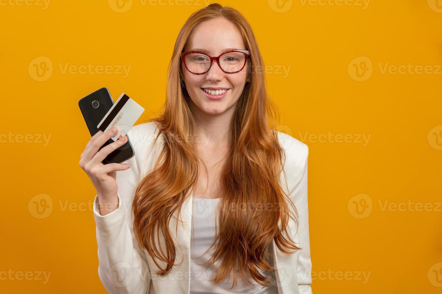ung, självsäker, framgångsrik och vacker rödhårig affärskvinna som köper med smartphonen på gult. yrke, karriär, jobb koncept. foto