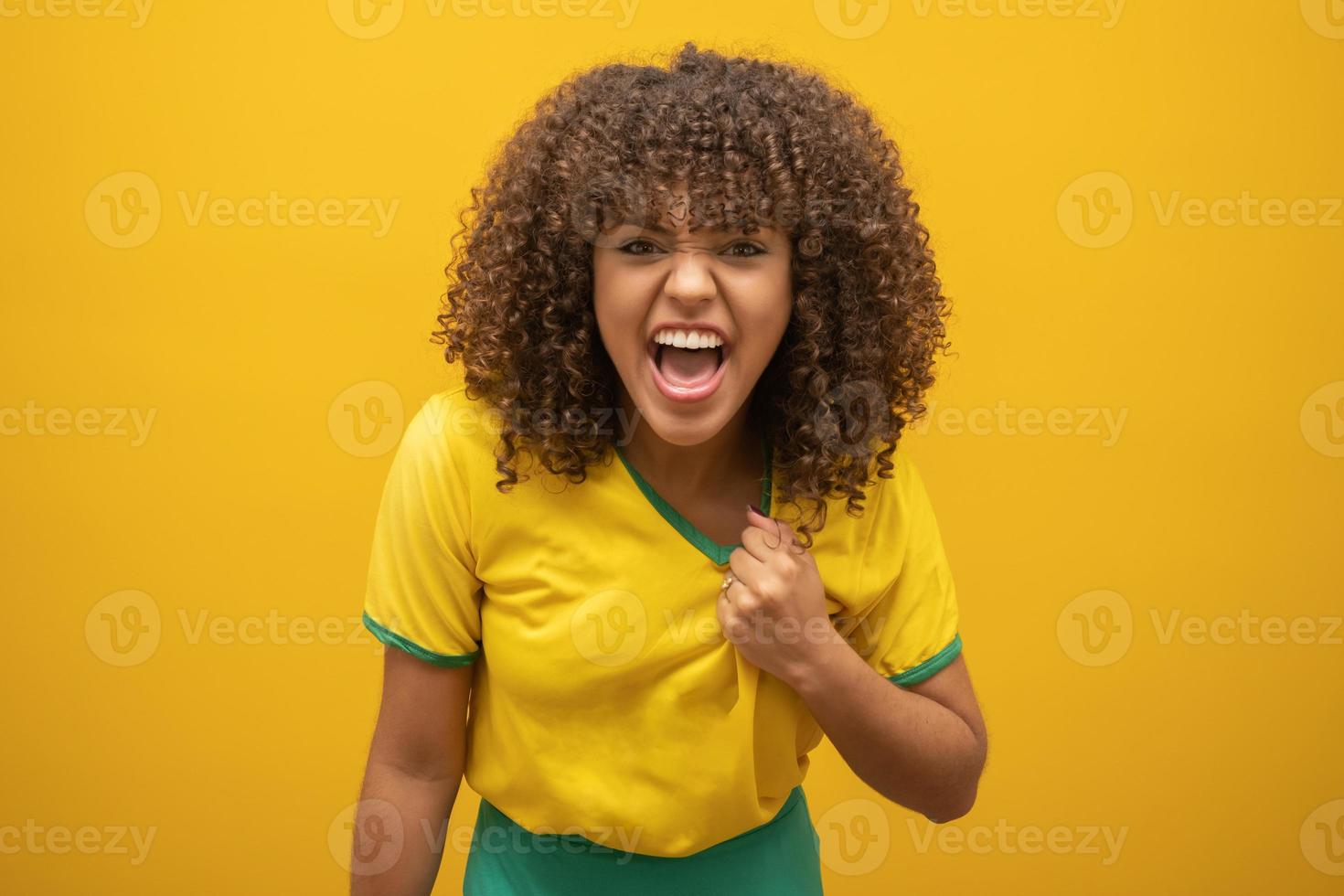 brasiliens anhängare. brasiliansk kvinna fan firar på fotboll fotbollsmatch på gul bakgrund. brasilianska färger. foto