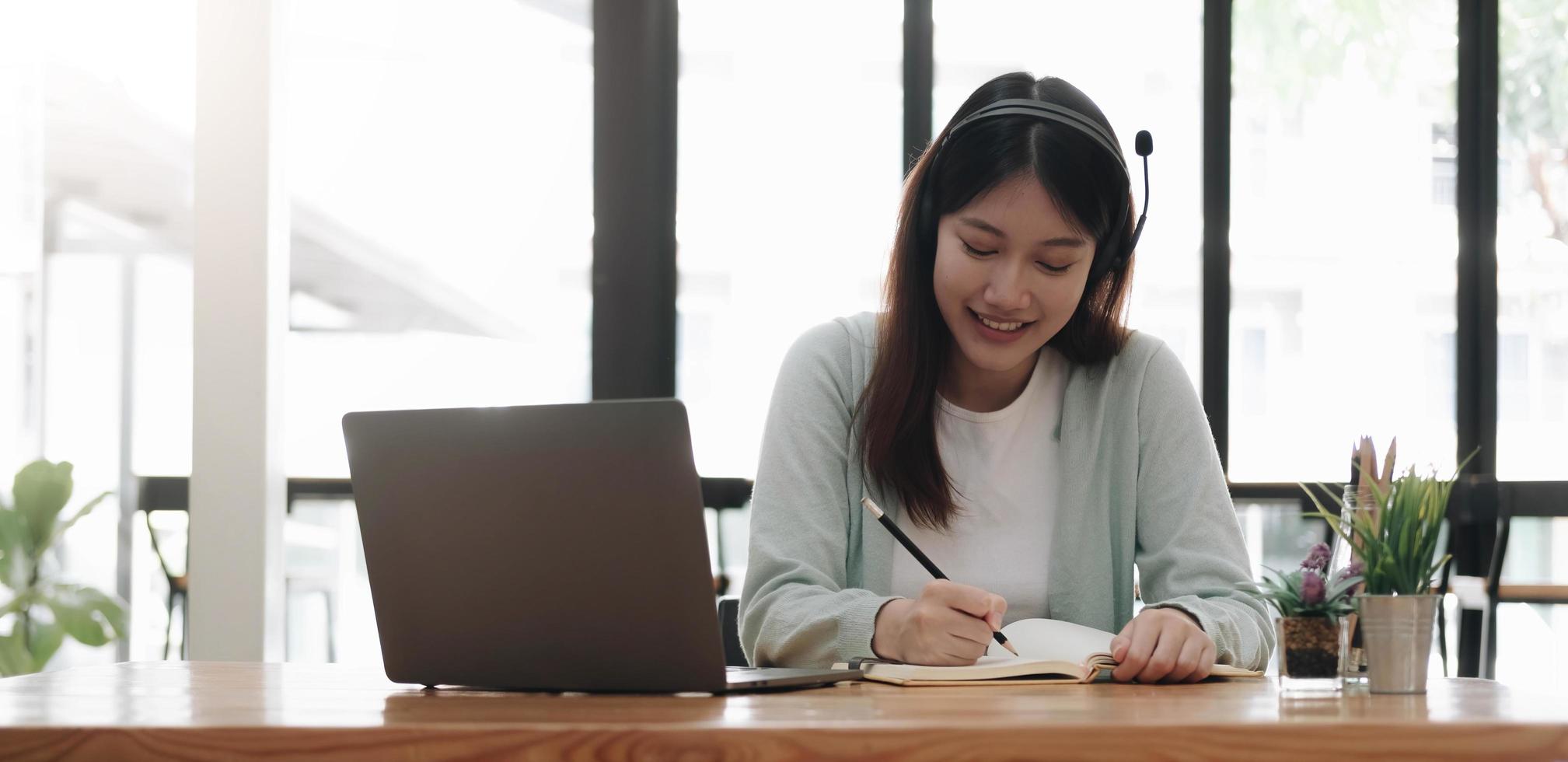 asiatisk kvinna som bär hörlurar studera online tittar på webbseminarium podcast på laptop lyssna lärande utbildning kurs konferenssamtal, eLearning koncept. foto