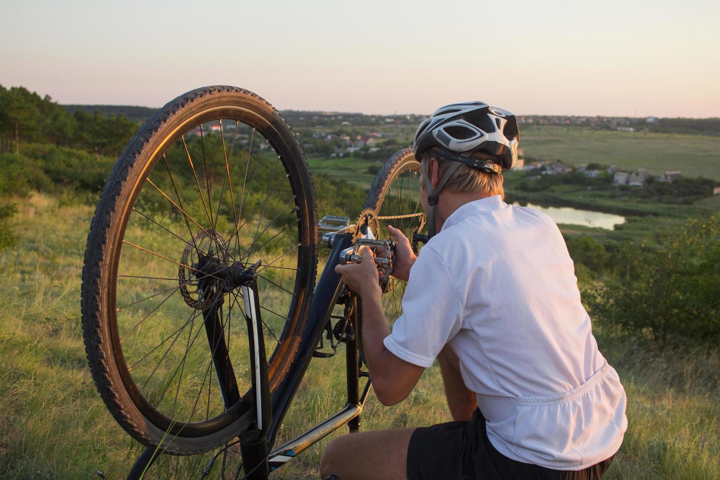 man justerar och inspekterar en cykel utomhus på kullen foto