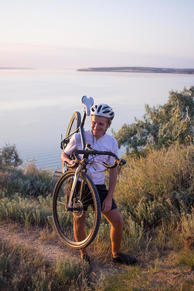 cykelryttare på professionell cykelcross cykeltur nedförsbacke, tall och sjö bakgrund foto