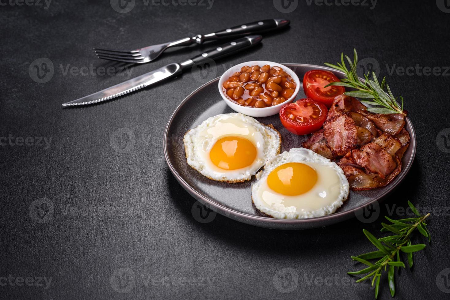 en utsökt näringsrik frukost med stekt ägg, bacon, bönor, ett glas juice, havrekakor, mjölk och sylt foto