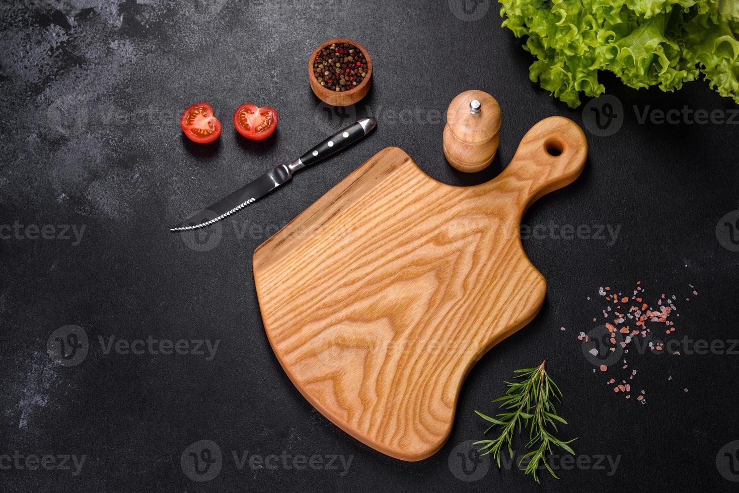 en skärbräda i trä med en kökskniv med kryddor och örter foto