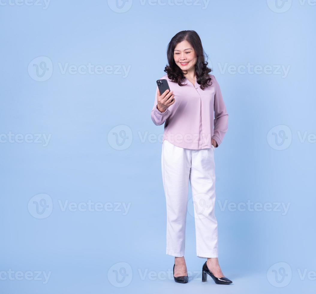 fullängdsbild av medelålders asiatisk kvinna på blå bakgrund foto