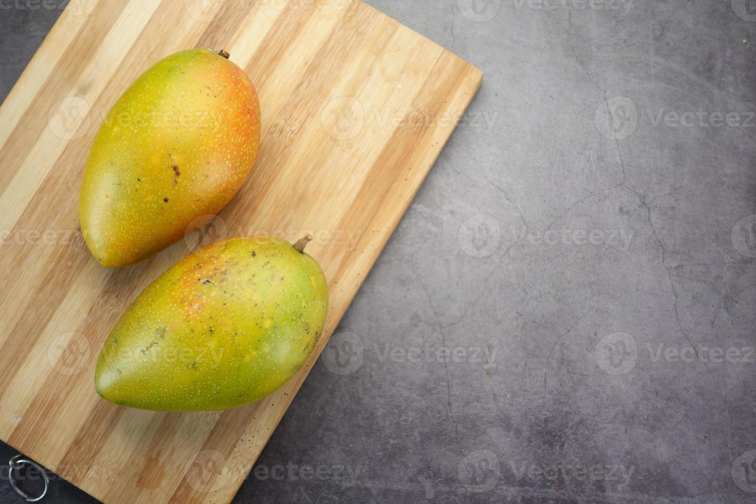 färsk grön mango på en skärbräda på svart foto