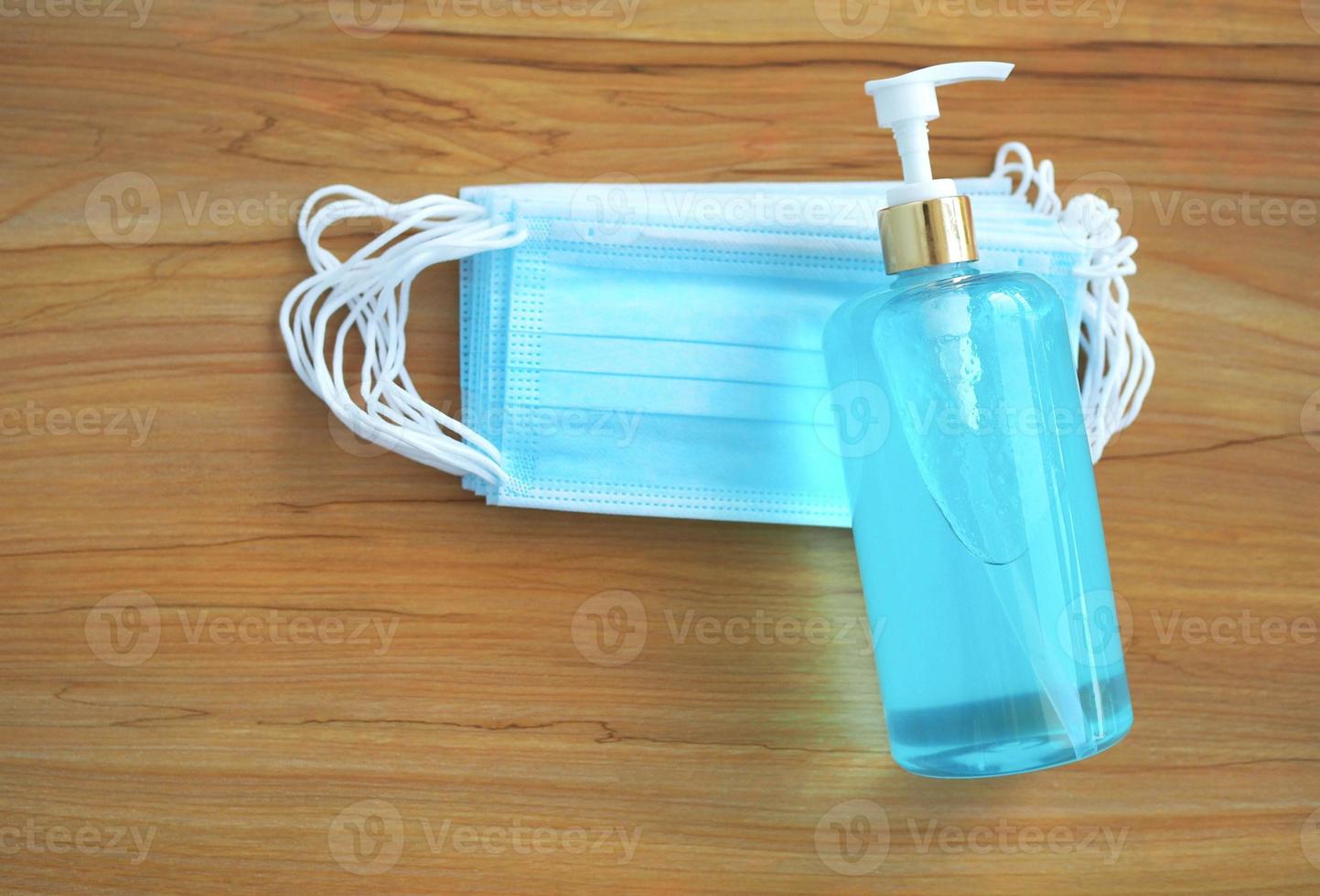 skydd mot coronavirus. en flaska handdesinfektionsmedel och en medicinsk skyddsmask på ett träbord. tvätta händerna hemma. foto