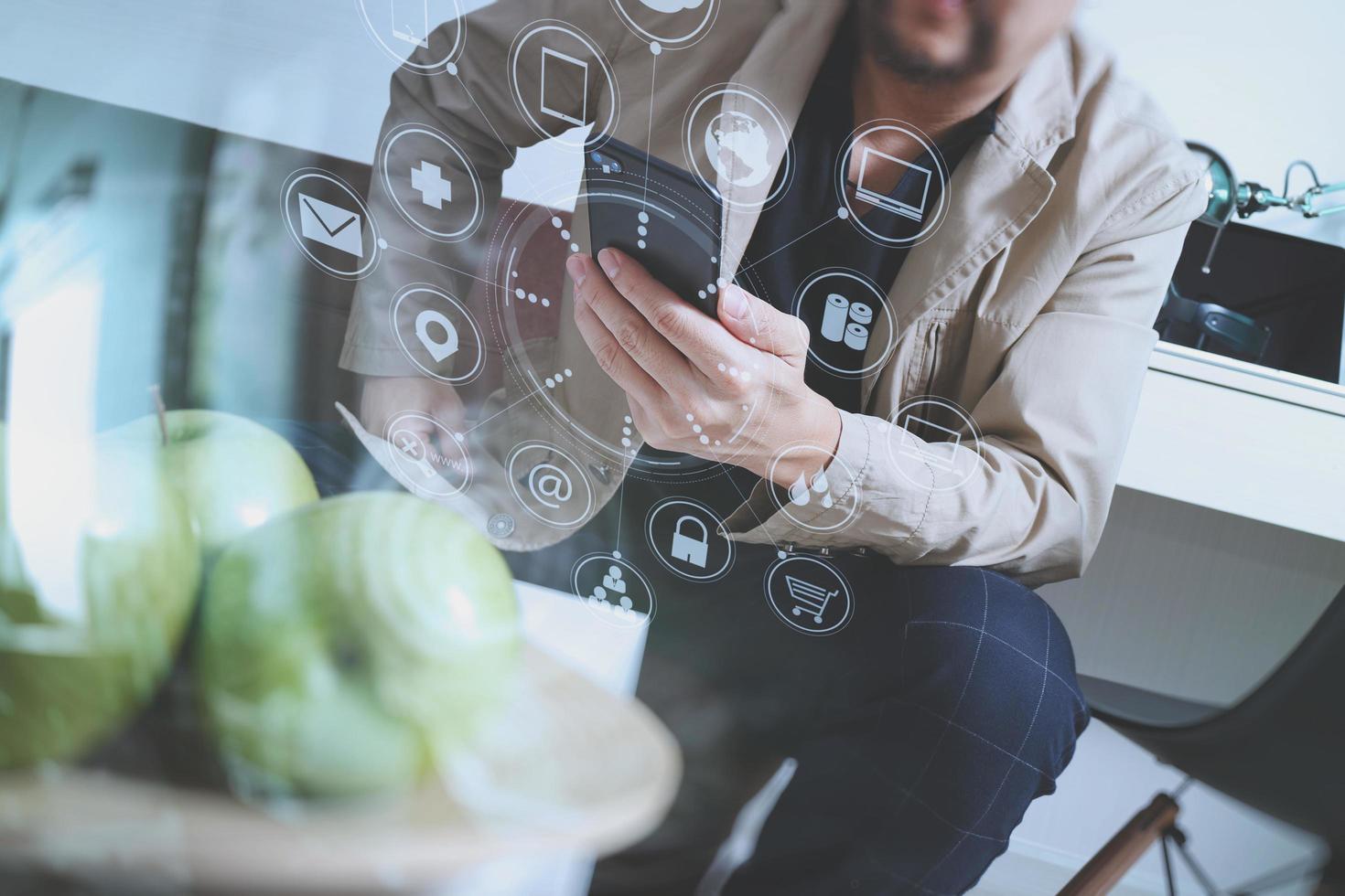 hipsterhand som använder smart telefon för mobila betalningar online-affärer, sitter på soffan i vardagsrummet, håller grönt äpple i träbricka, virtuellt datorgränssnitt omni channel foto