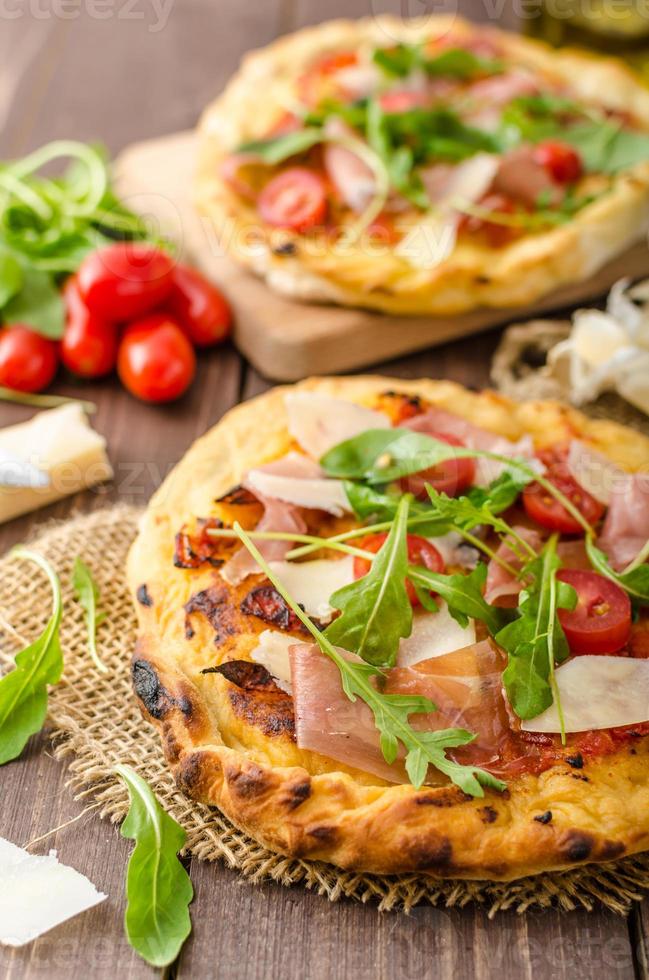 italiensk pizza med parmesanost, prosciutto och ruccola foto