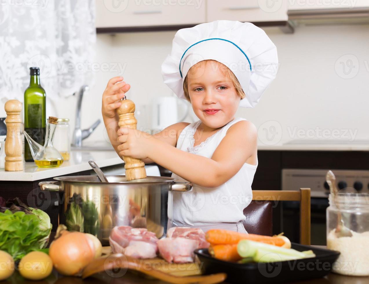 barn matlagning soppa i panna foto