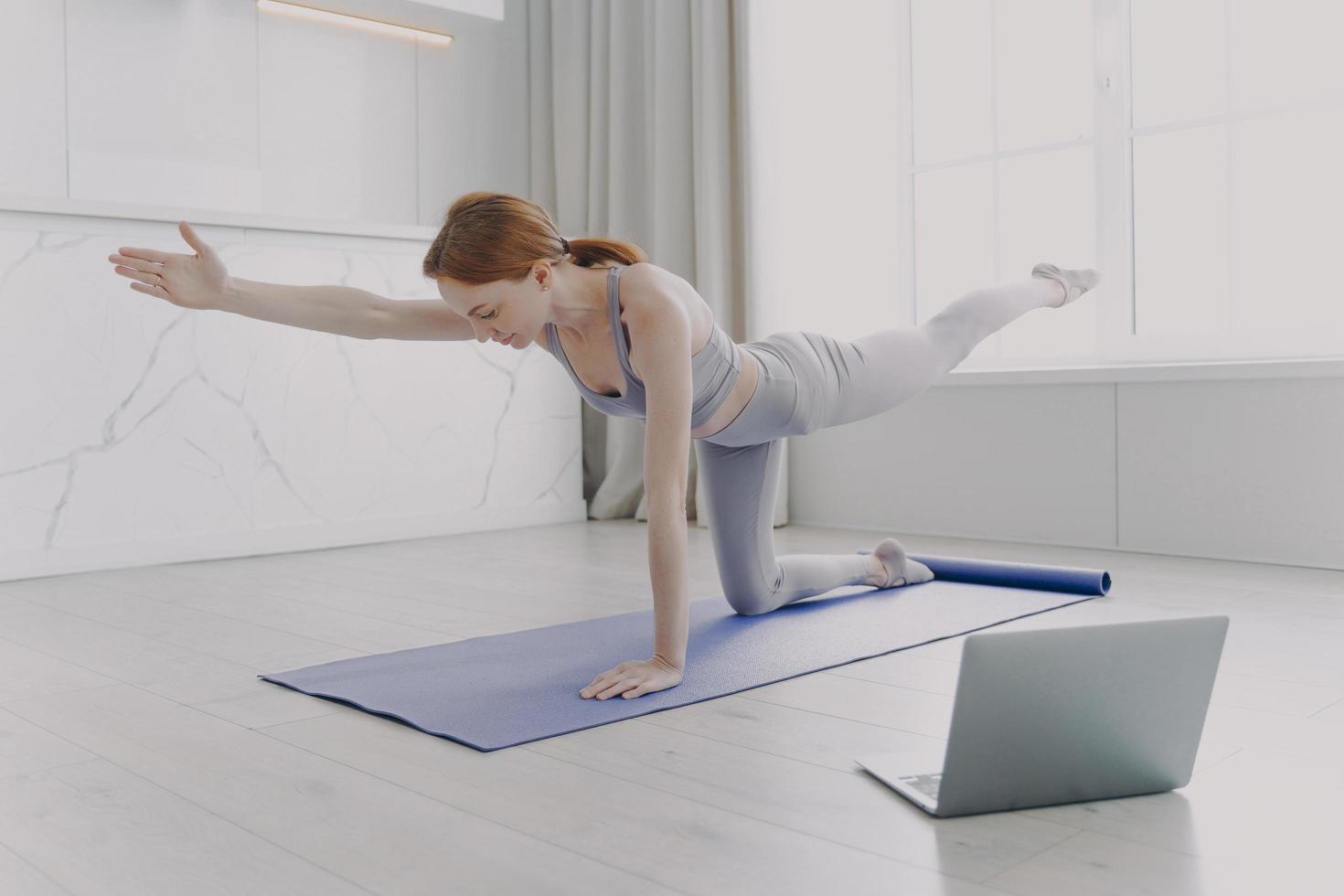 ung kvinna njuter av yoga genom videolektioner. morgonträning och sportrutinkoncept. foto