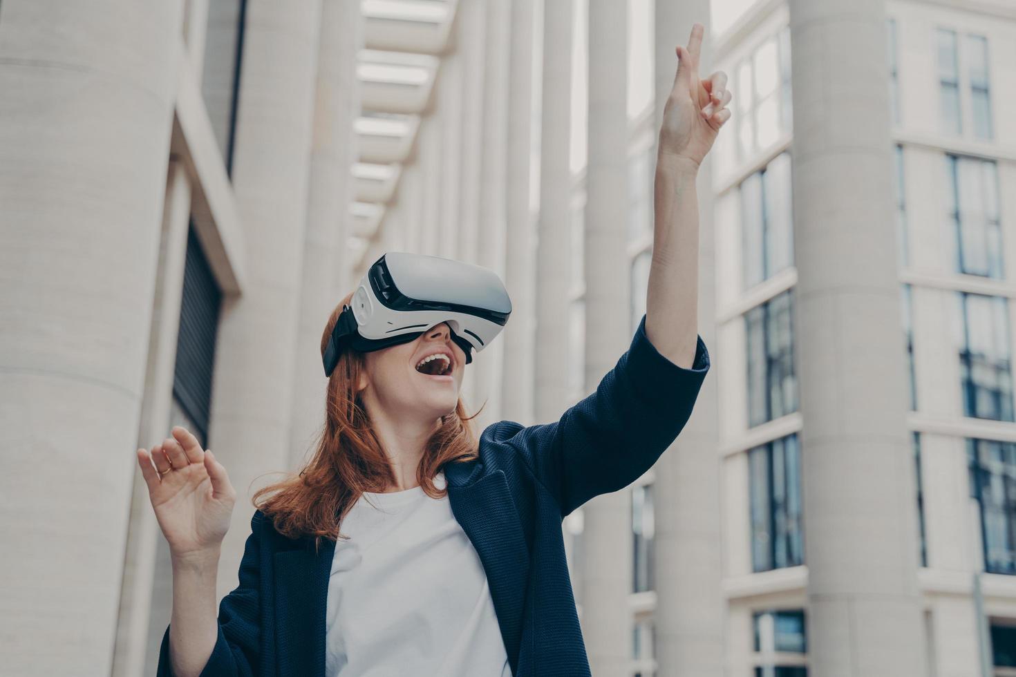 upphetsad kvinnlig företagare som bär bärbara vr-glasögon och försöker röra något i virtuell verklighet foto