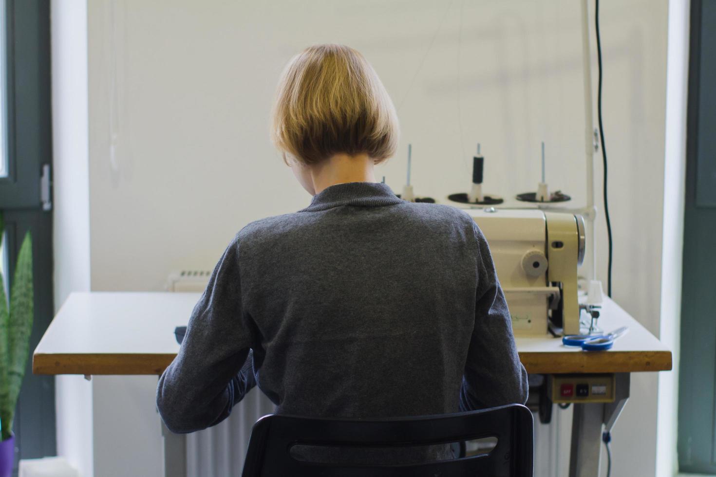 sömmerska på jobbet på bordet, skräddare kvinna arbete i studio med kläder foto