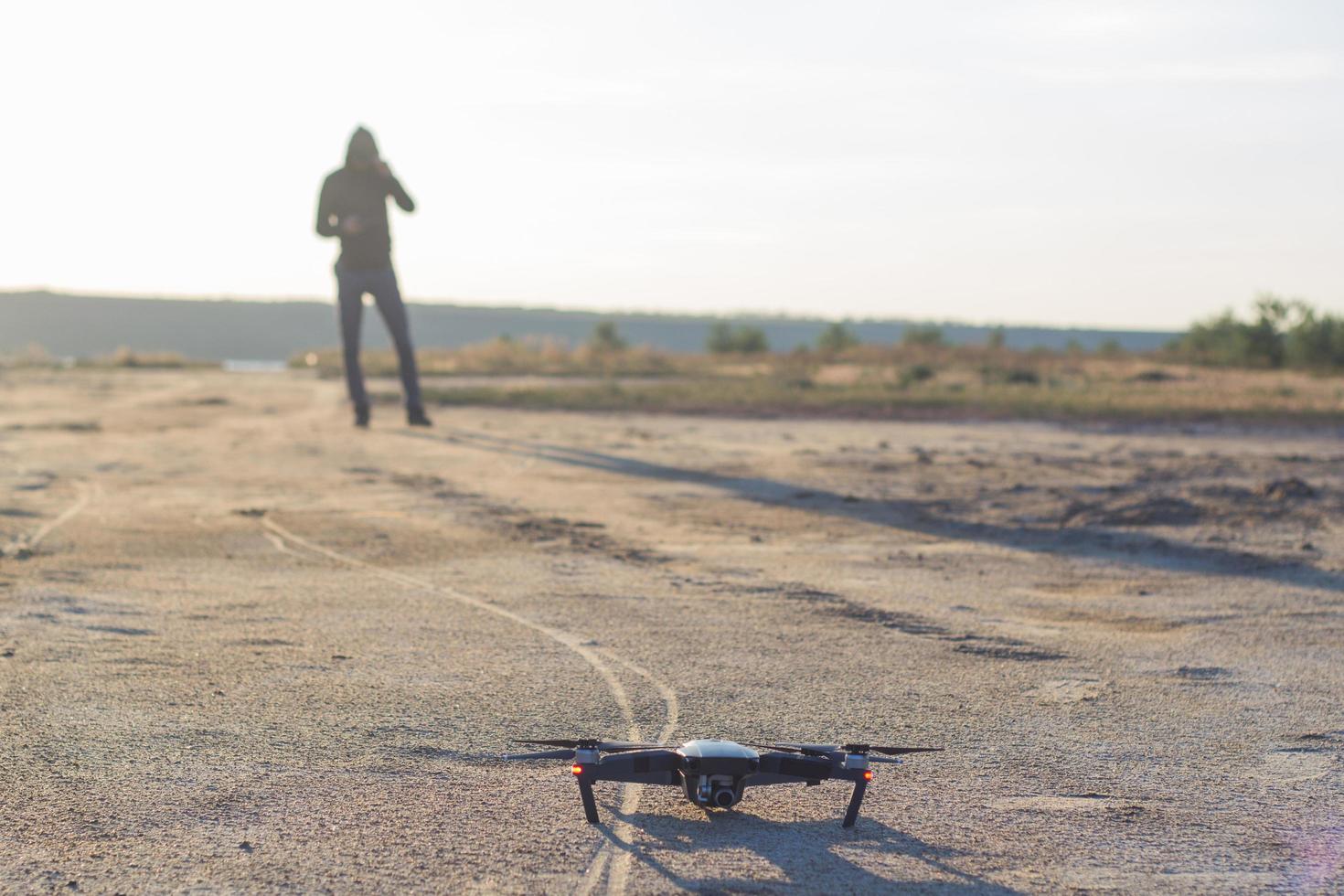 bild av svart flådande quadrocopter dron och pilot siluette i solnedgång ljus bakgrund, turist användning dron helikopter för att fotografera eller filma ökenlandskap foto