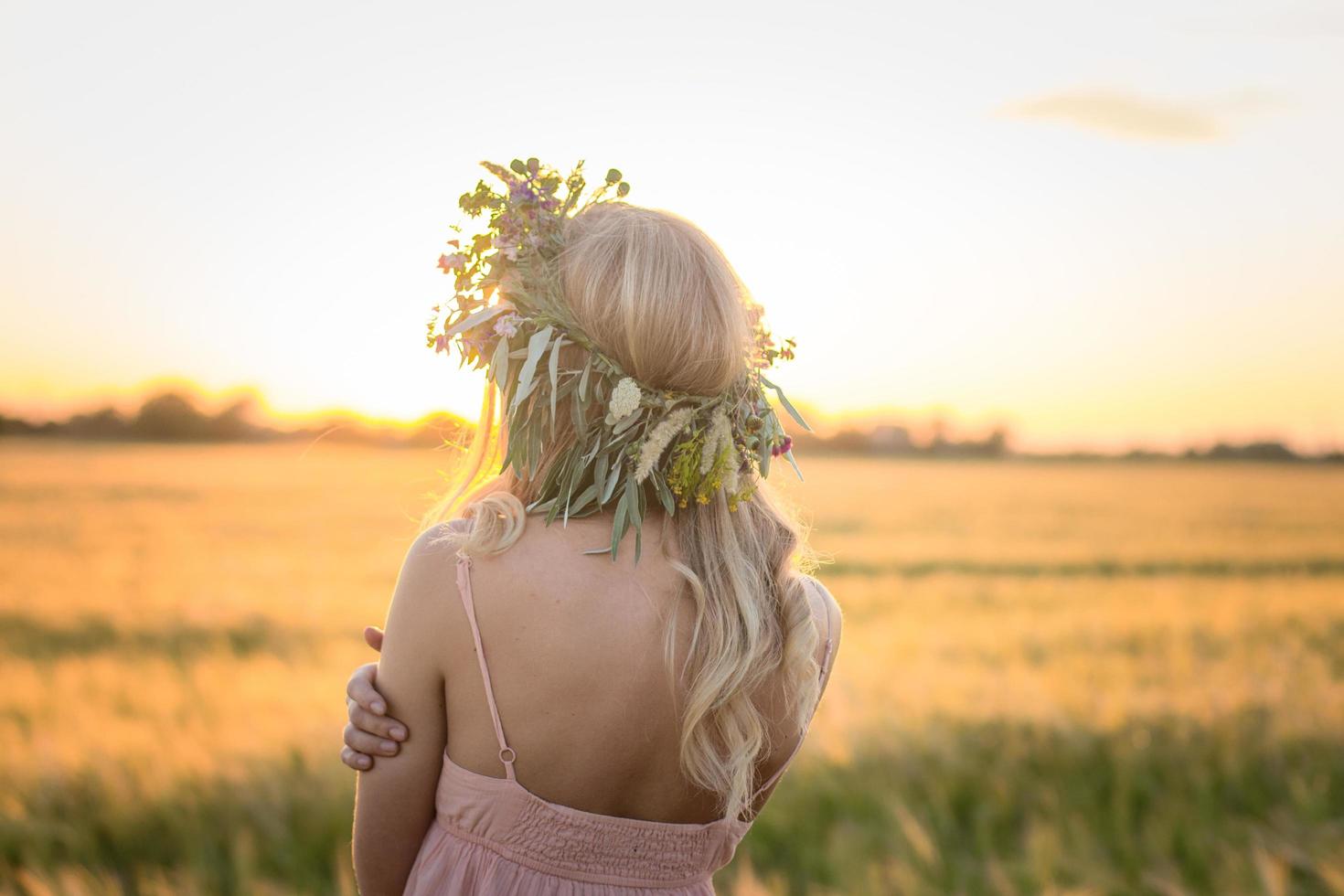 porträtt av ung kvinna som har det bra i vetefält under solnedgången, dam i huvudet blomkrans under foto