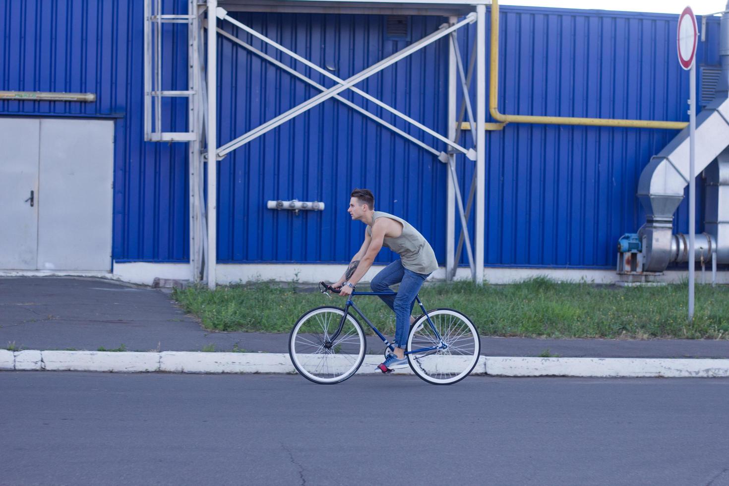 ung, man promenad med fixie cykel, urban bakgrund, bild av hipster med cykel i blå färger foto