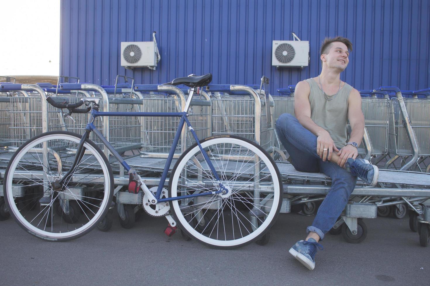 ung, man promenad med fixie cykel, urban bakgrund, bild av hipster med cykel i blå färger foto