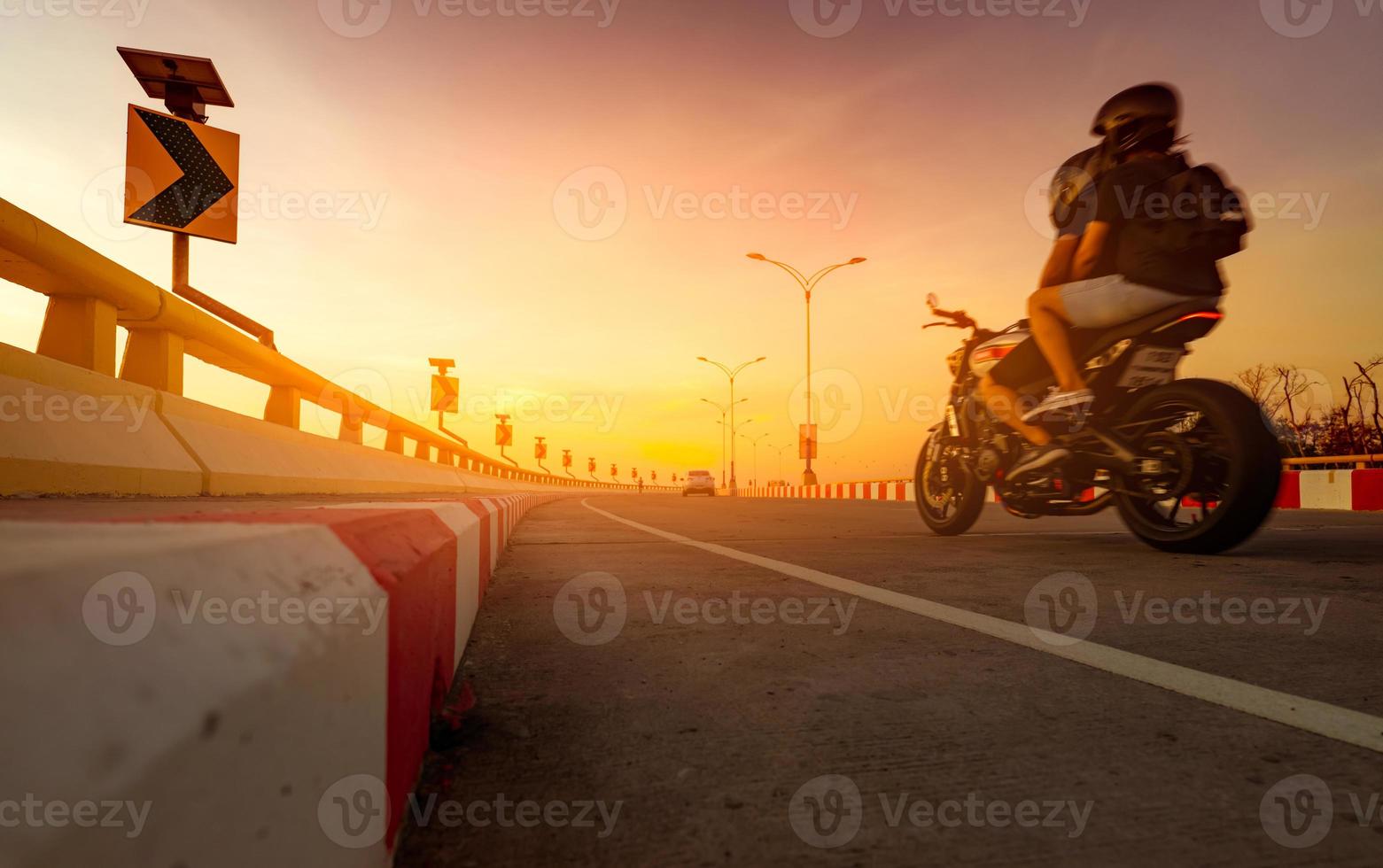 solpanel energi på gul kurva trafikskylt och rörelseoskärpa av biker rider motorcykel på kurva väg. roadtrip på sommarlovet. sommarresa av kärlekspar med motorcykel. på väg hem. foto