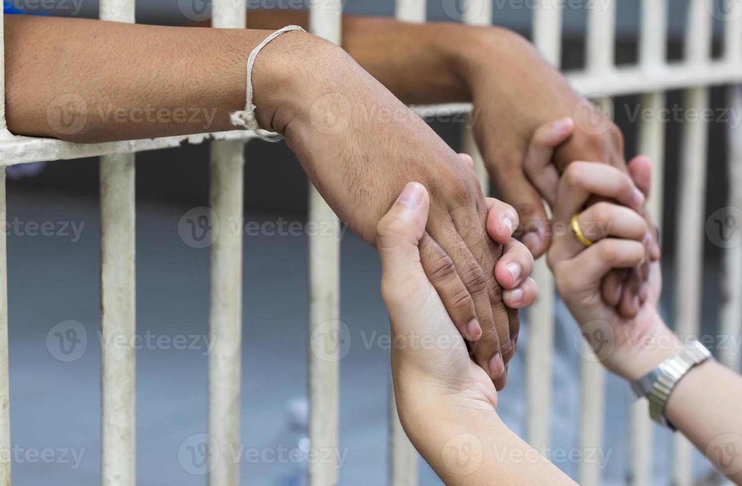 kvinna som håller handen på en manlig fånge i en vit bur. foto