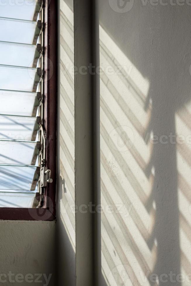 solen skiner genom spjällfönstren in i betongväggen. foto