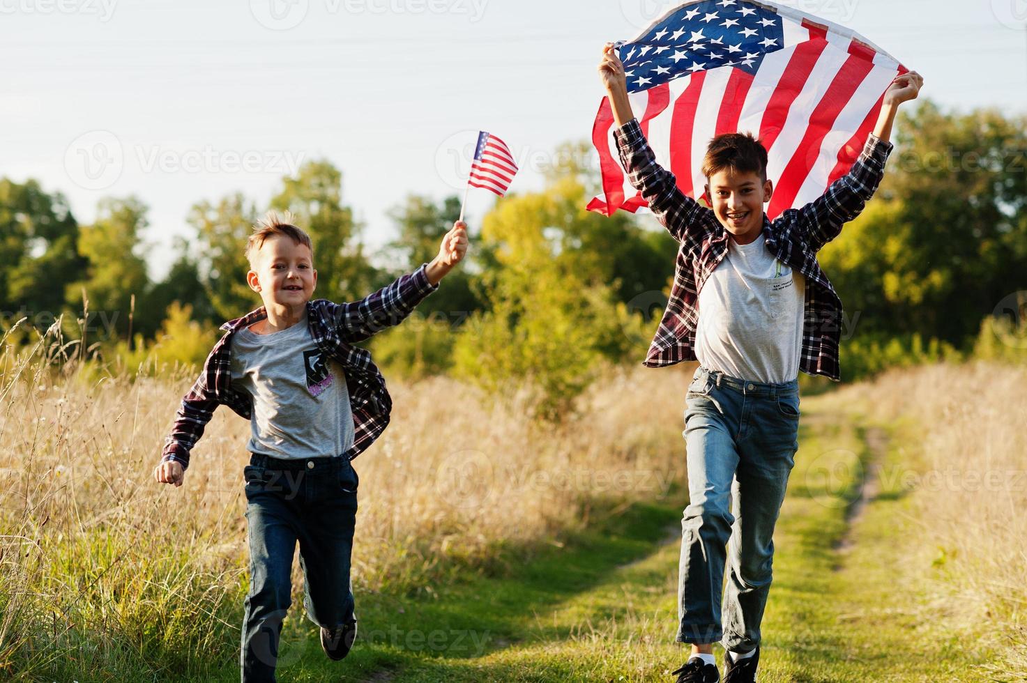 två bröder som springer med USA-flaggan. amerika semester. stolt över att vara landets barn. foto