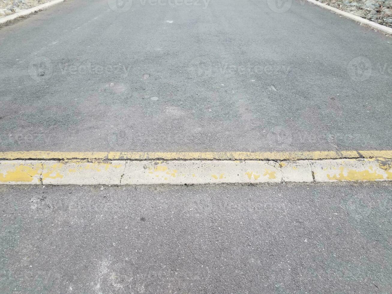 förhöjd asfalt eller trottoarväg med gul trottoarkant eller ramp foto