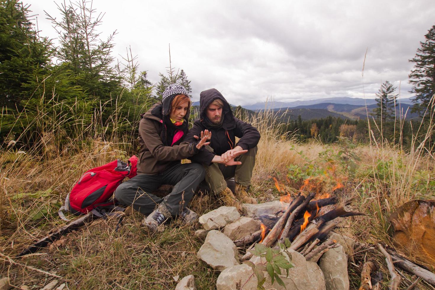 ungt par vandrare med termoskoppar i skogen, resenärer på berg som dricker te eller kaffe foto