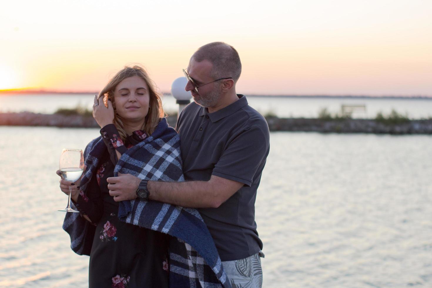 par älskare dricker vin och har bra tid på stranden, solnedgång bakgrund foto