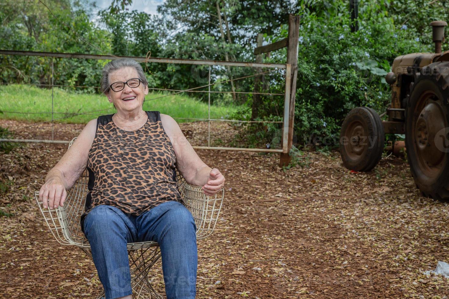 senior glad gammal bondekvinna med glasögon som ler och tittar på kameran foto