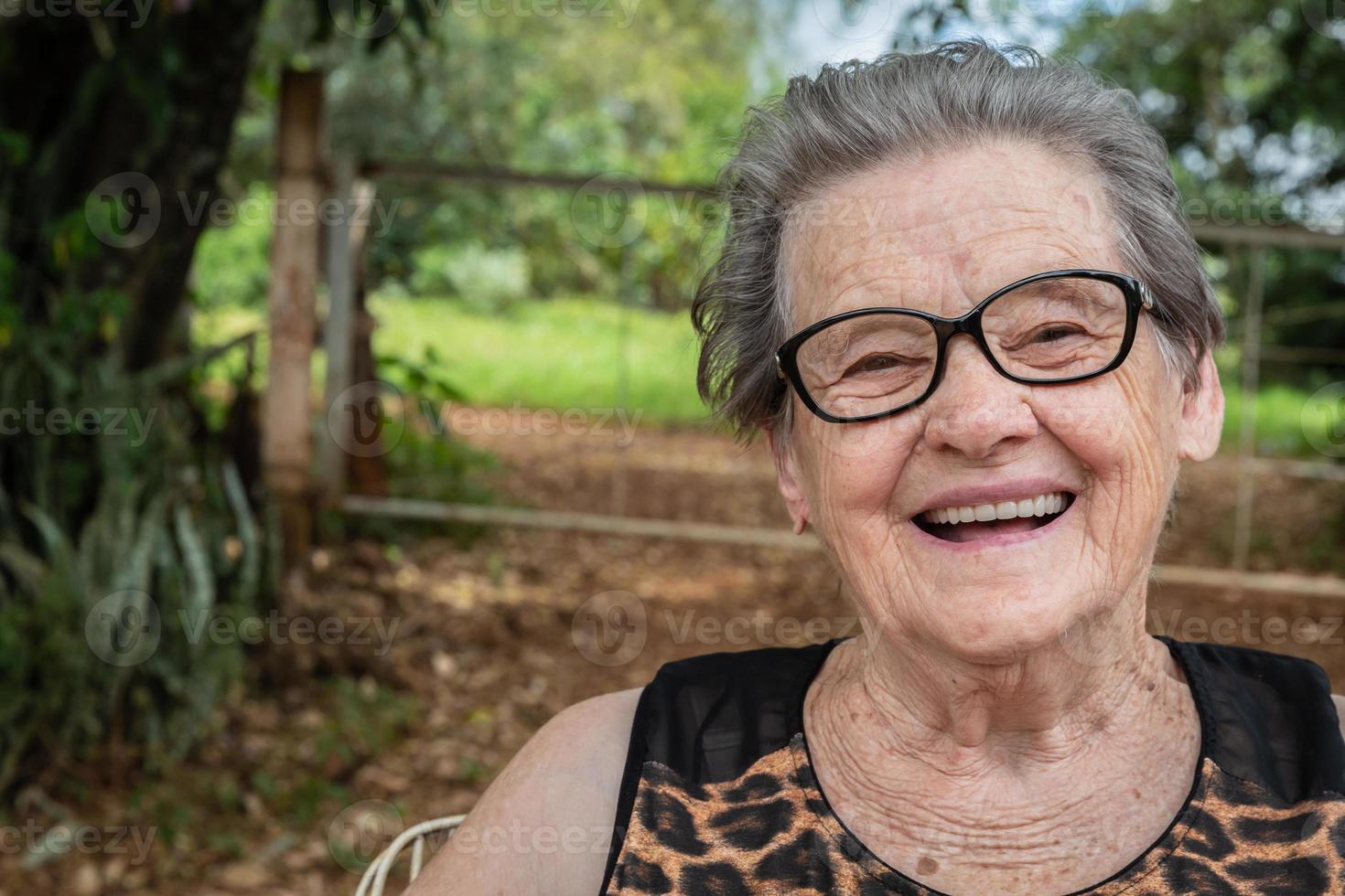 senior glad gammal bondekvinna med glasögon som ler och tittar på kameran foto