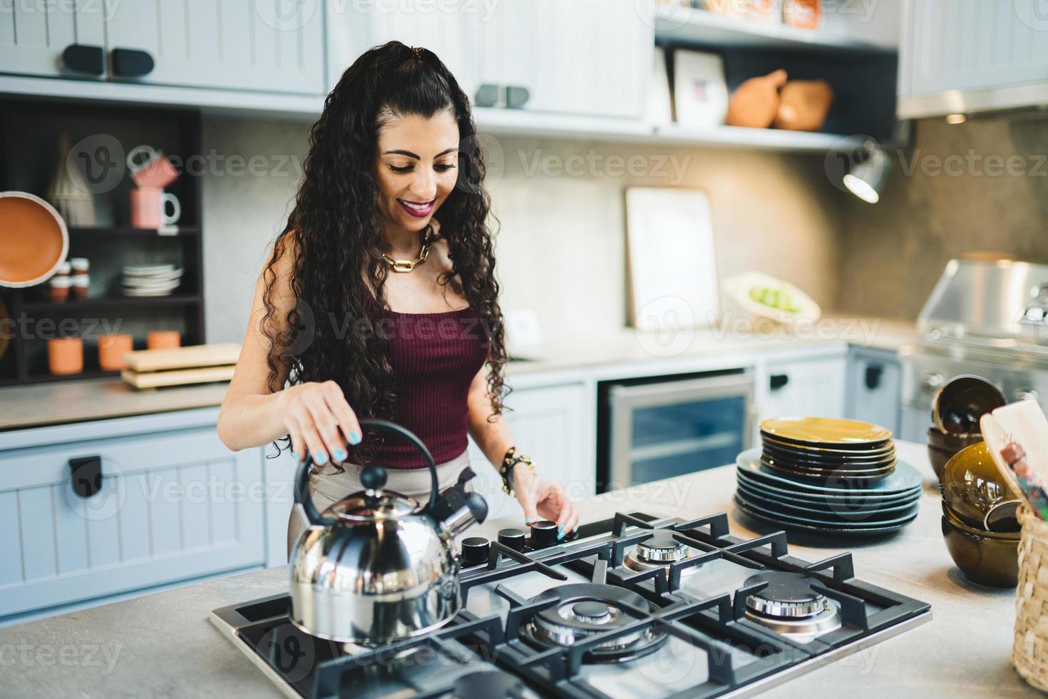 ung latinsk kvinna hemma förbereder te i köket. foto