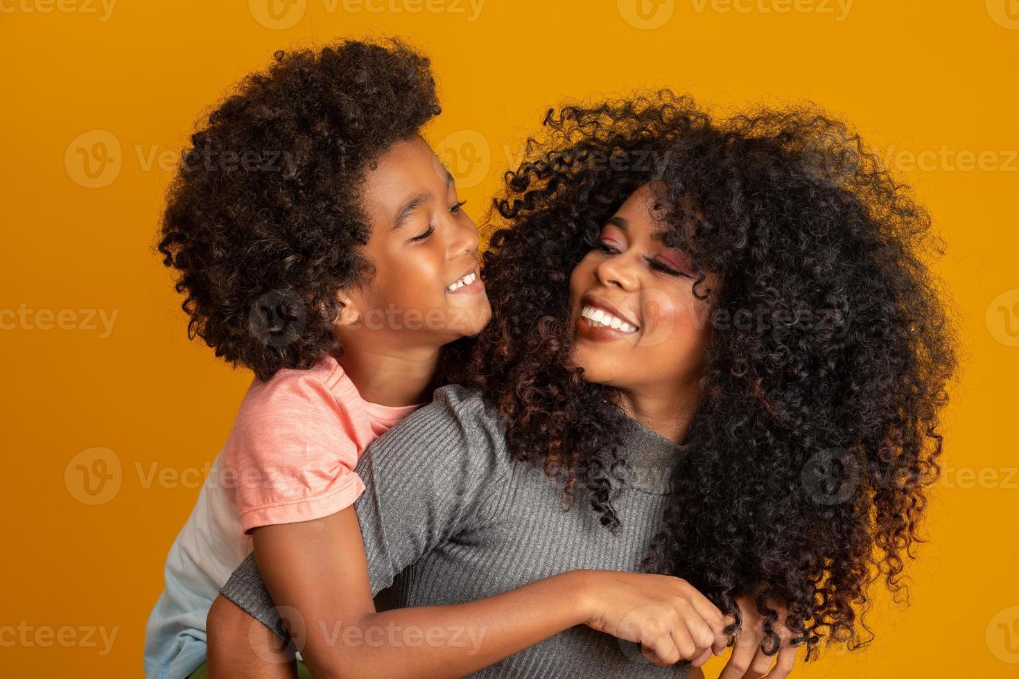 porträtt av ung afroamerikansk mor med barnson. gul bakgrund. brasiliansk familj. foto