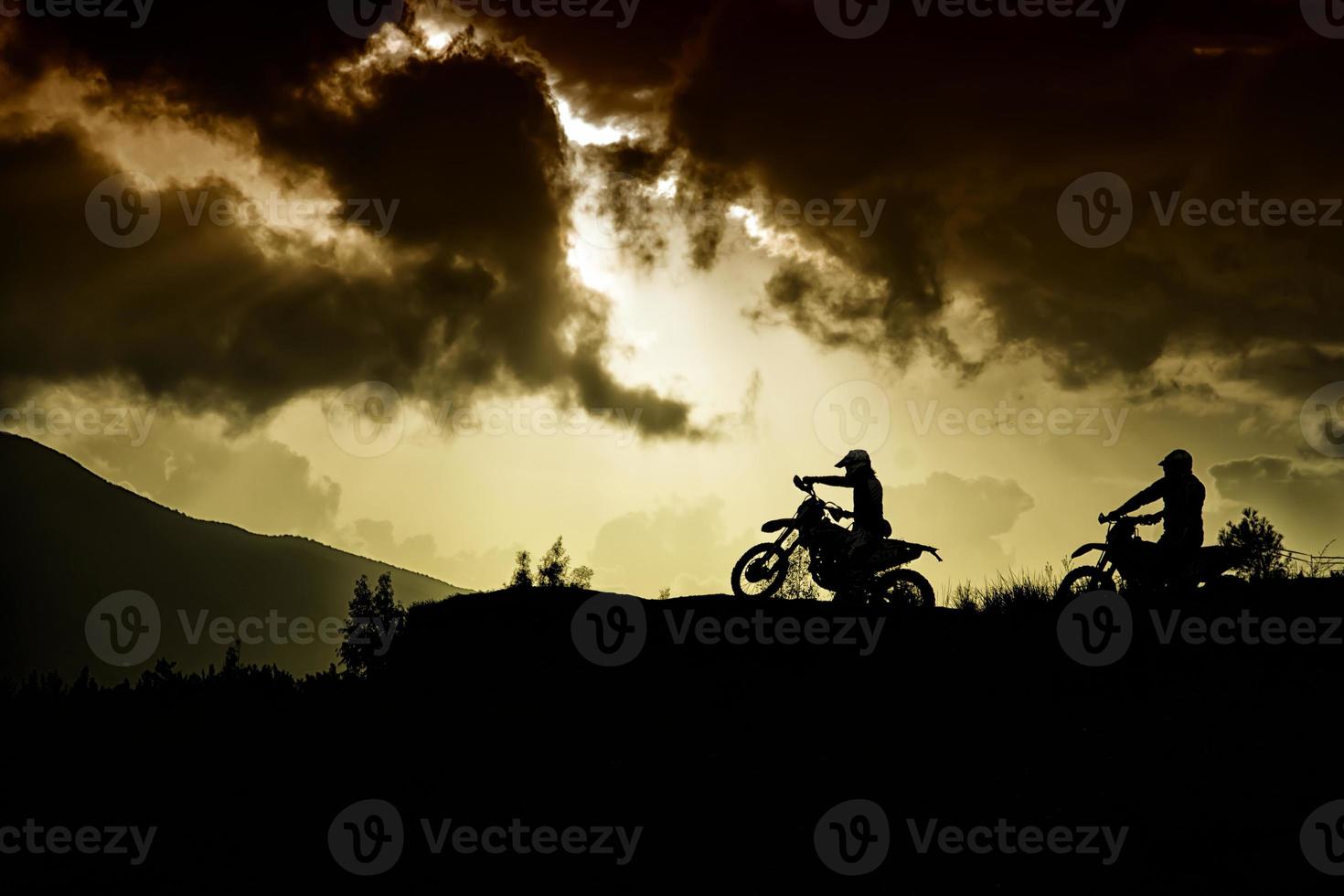 två motorcyklister på toppen av en kulle foto