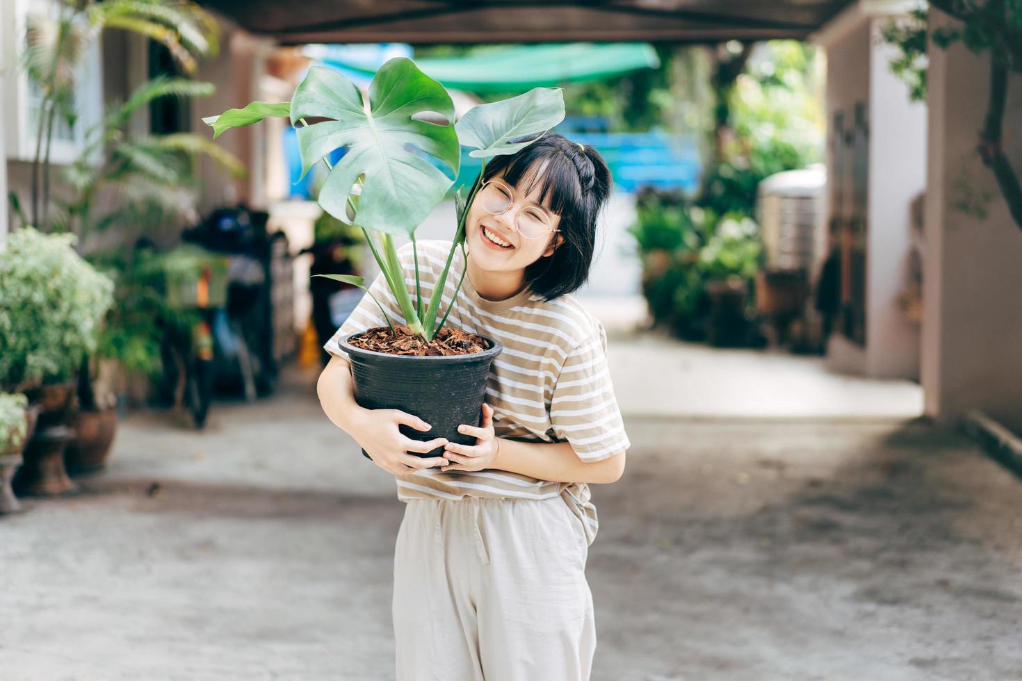 porträtt av ung vuxen asiatisk kvinna med monstera träd. foto