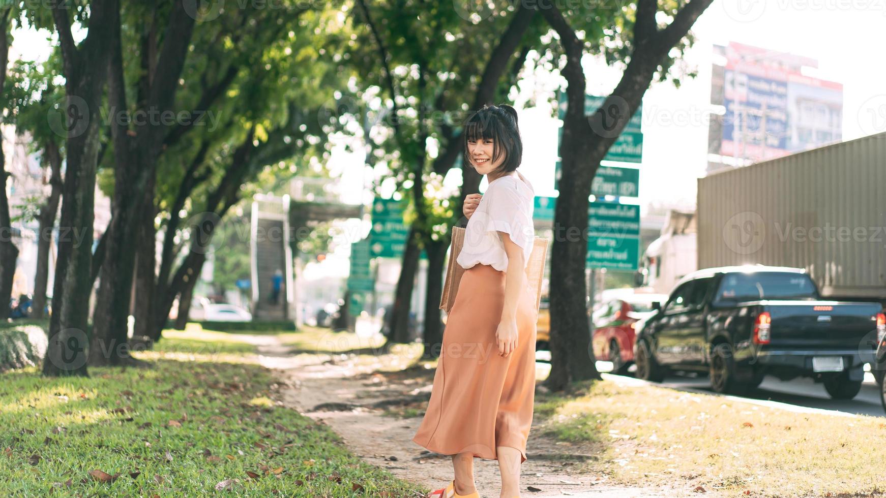 ung vuxen affärs asiatisk kvinna promenader i offentlig park utomhus. foto