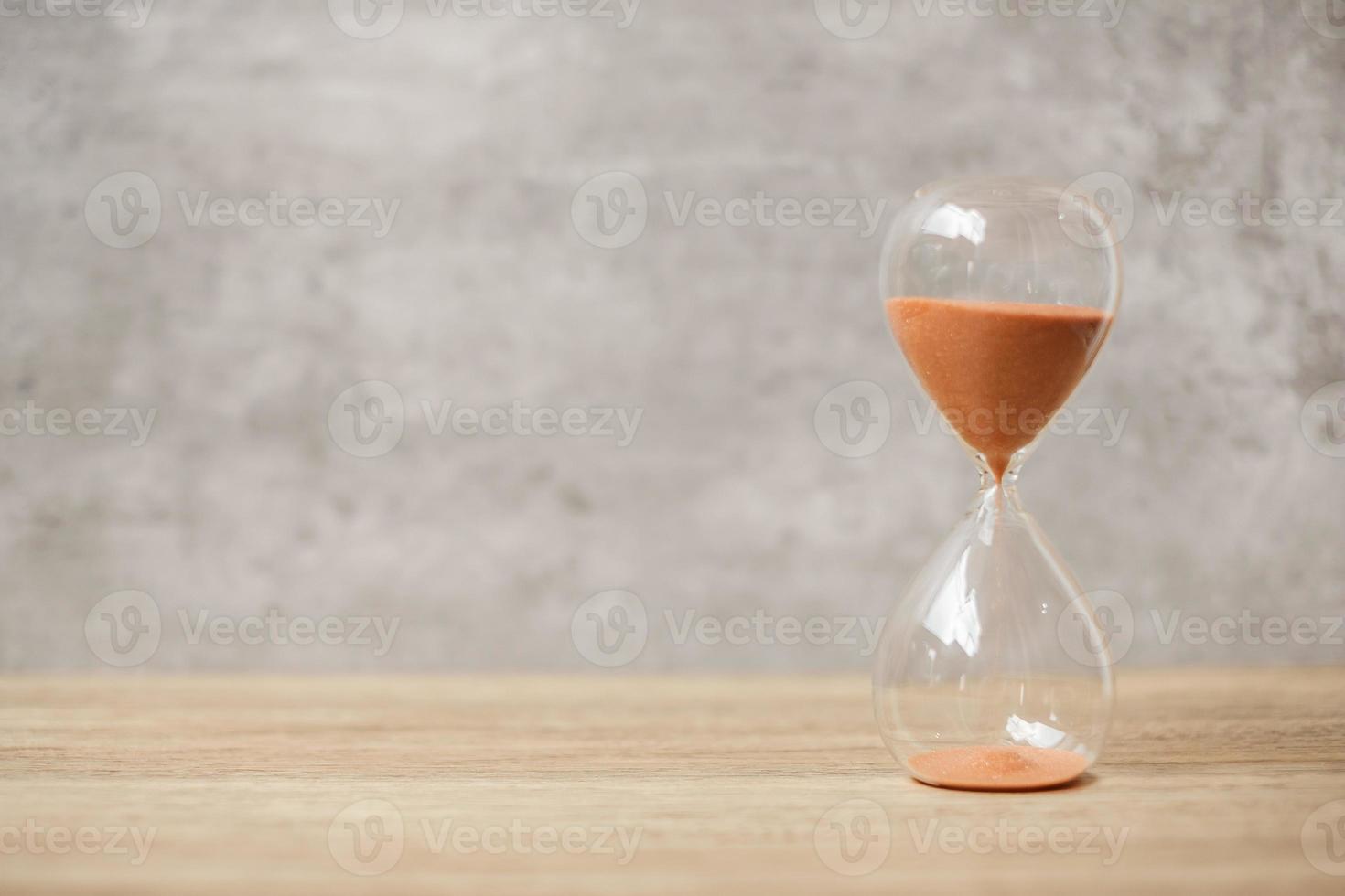 timglas på bordet, sand som rinner genom glödlampan av sandglas som mäter tiden som går. nedräkning, deadline, livstid och pensionskoncept foto