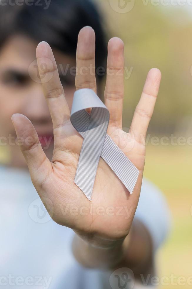 hjärncancer medvetenhet månad, kvinna hand som håller grå färg band för att stödja människor som lever. hälsovård och världen cancer dag koncept foto