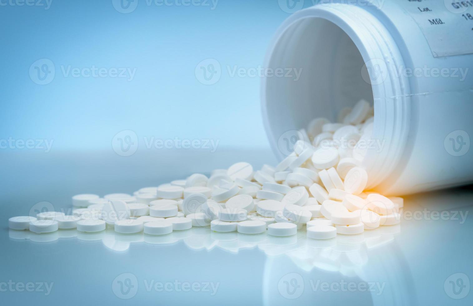 vita tabletter piller spills ut från vit plastflaska behållare. läkemedelsindustri. apoteksprodukt. global sjukvård. droganvändning på sjukhus eller apotek. hälsobudget. farmaci. foto