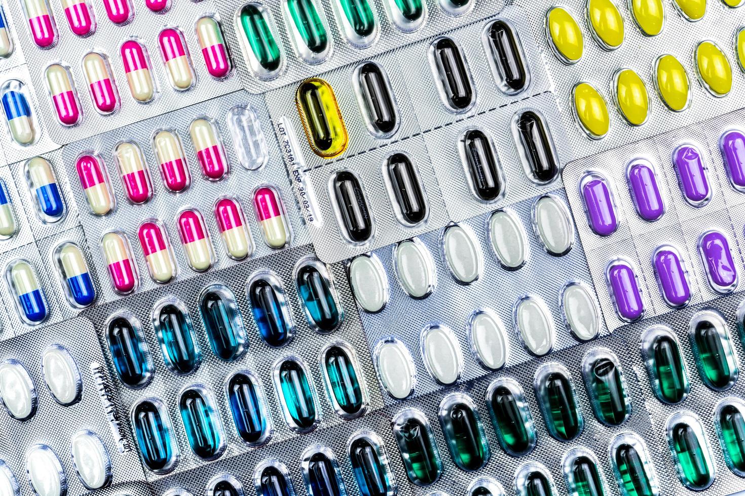 färgglada tabletter och kapslar piller i blisterförpackning arrangerad med vackert mönster med flare ljus. läkemedelsindustrin koncept. apotek apotek. resistens mot antibiotika. defekt. foto