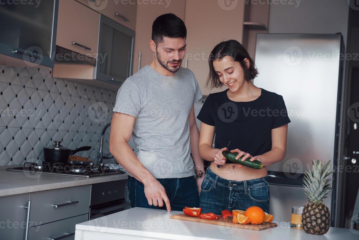 pratar med varandra under processen. ungt par i det moderna köket hemma på deras helgtid på morgonen foto