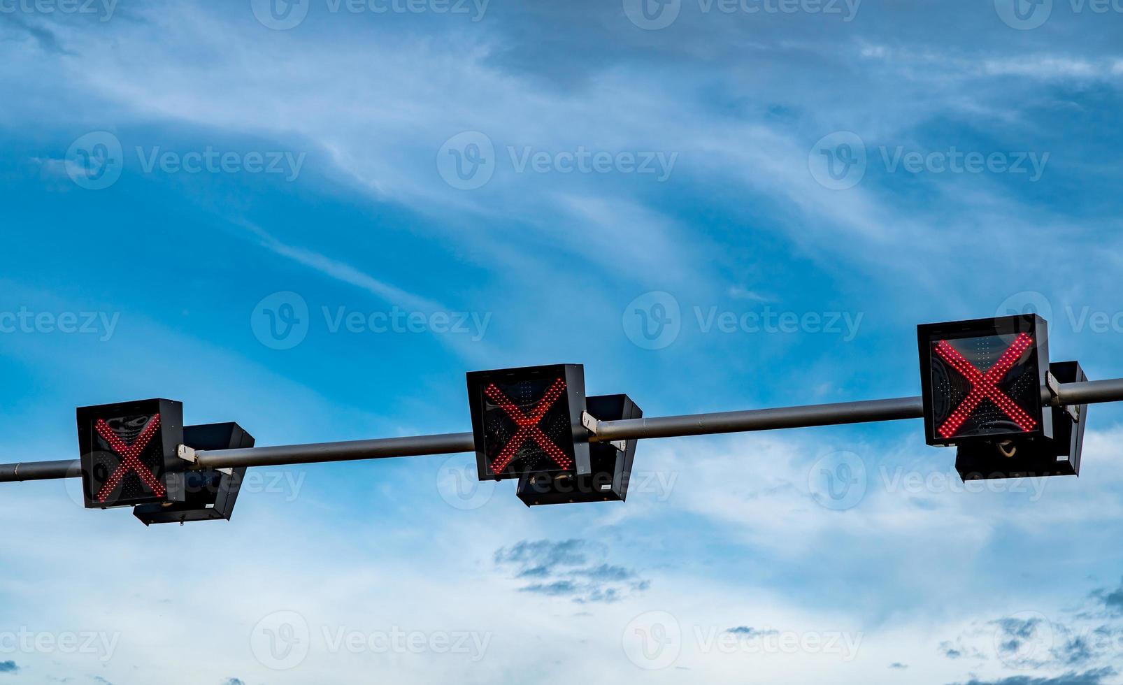 trafiksignal ljus med röd färg på korset tecken på blå himmel och vita moln bakgrund. fel tecken. ingen infartstrafikskylt. röda korset vägledning stopp kör trafikljus. varningstrafikljus. foto
