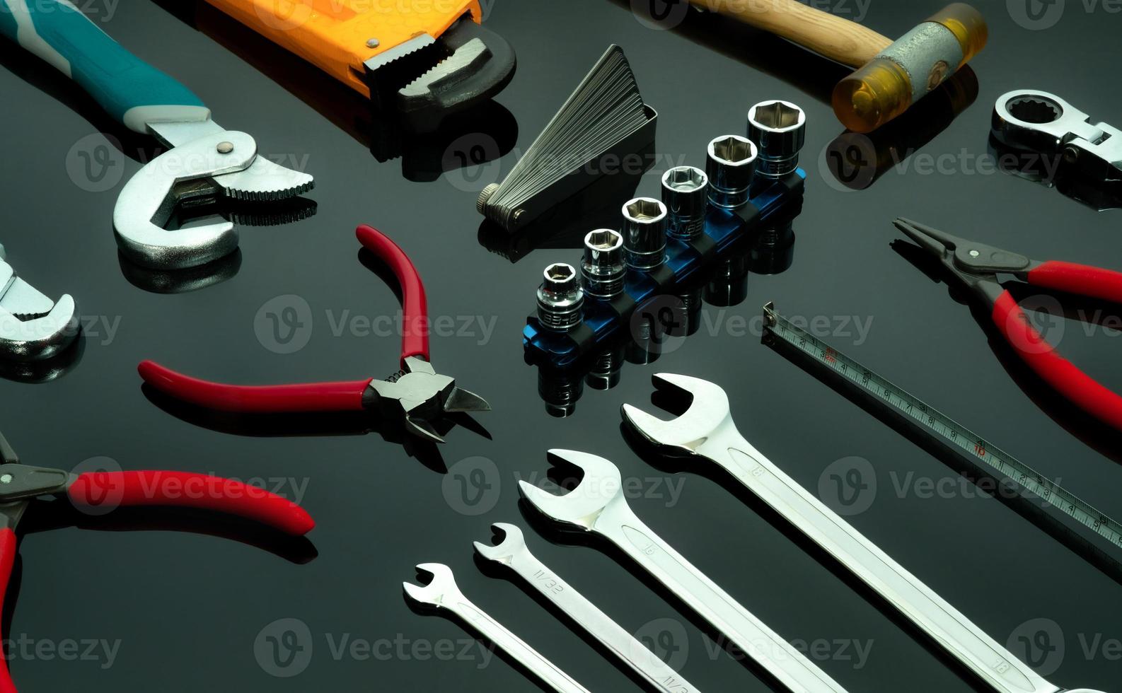 uppsättning mekaniker verktyg på mörk bakgrund. kromnycklar eller nycklar, insexhylsa, ändtång, låstång, tång, känselmått, böjd skiftnyckel och hammare. skiftnyckel i kromvanadin. foto