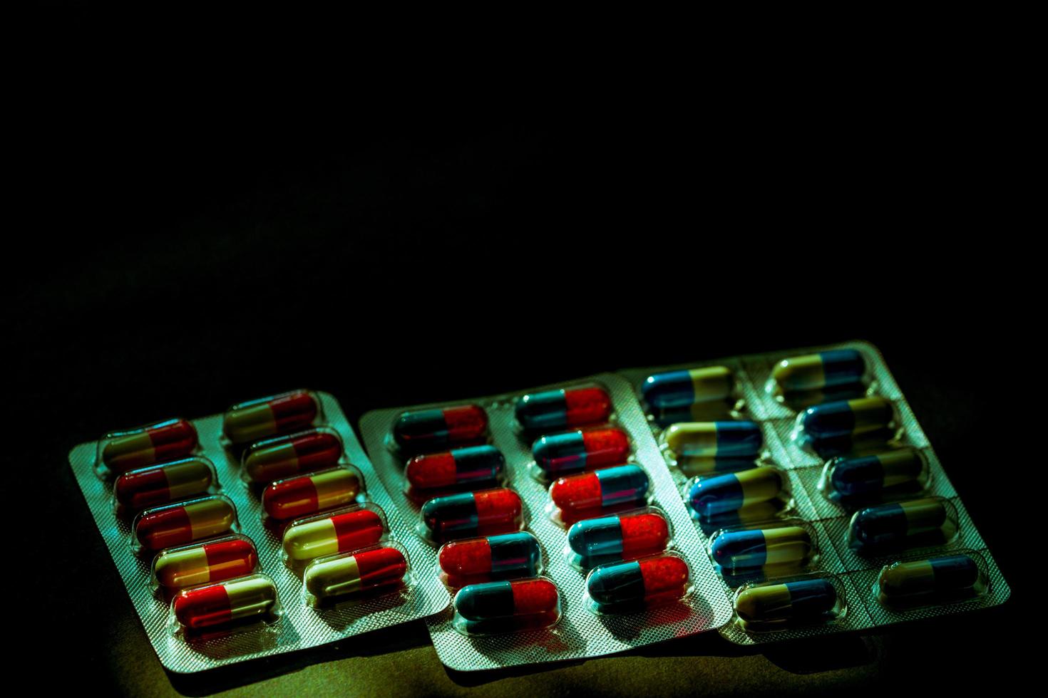 färgglada antibiotika kapsel piller i blisterförpackning på mörk bakgrund med kopia utrymme. medicin för infektioner sjukdom. antibiotikadroganvändning med rimliga. läkemedelsresistens och hälsokoncept. foto