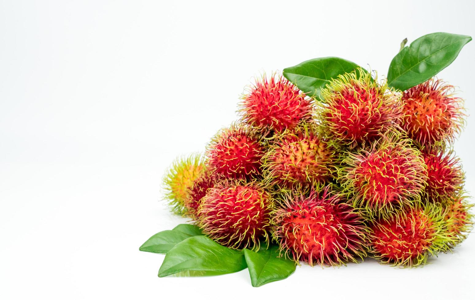 färsk röd mogen rambutan nephelium lappaceum med blad isolerad på vit bakgrund. thai dessert söta frukter. foto