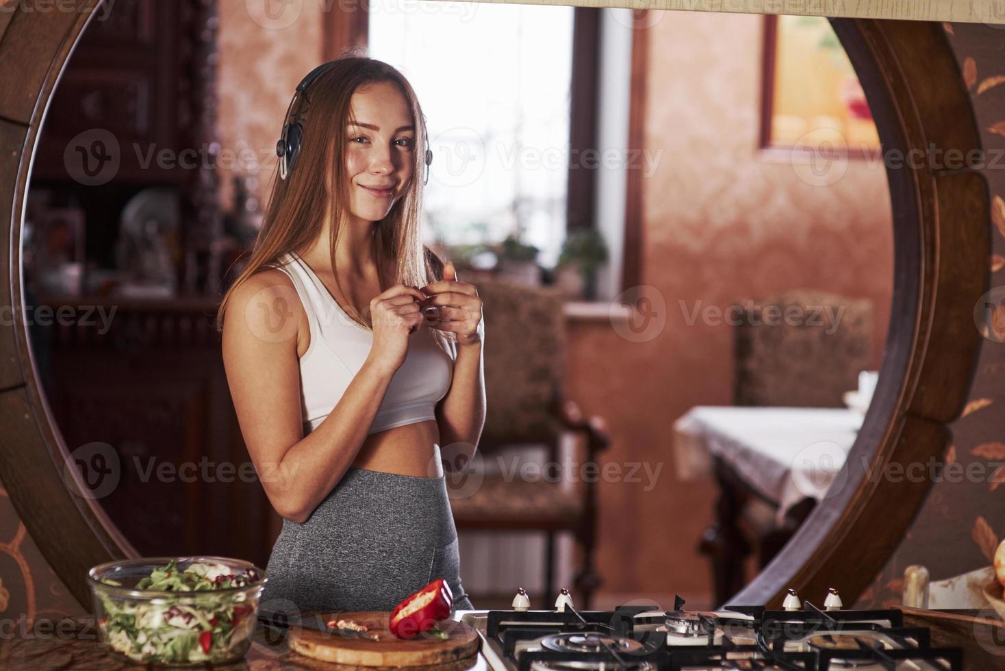 glad tjej. ganska ung kvinna som står i det moderna köket nära gasspis foto