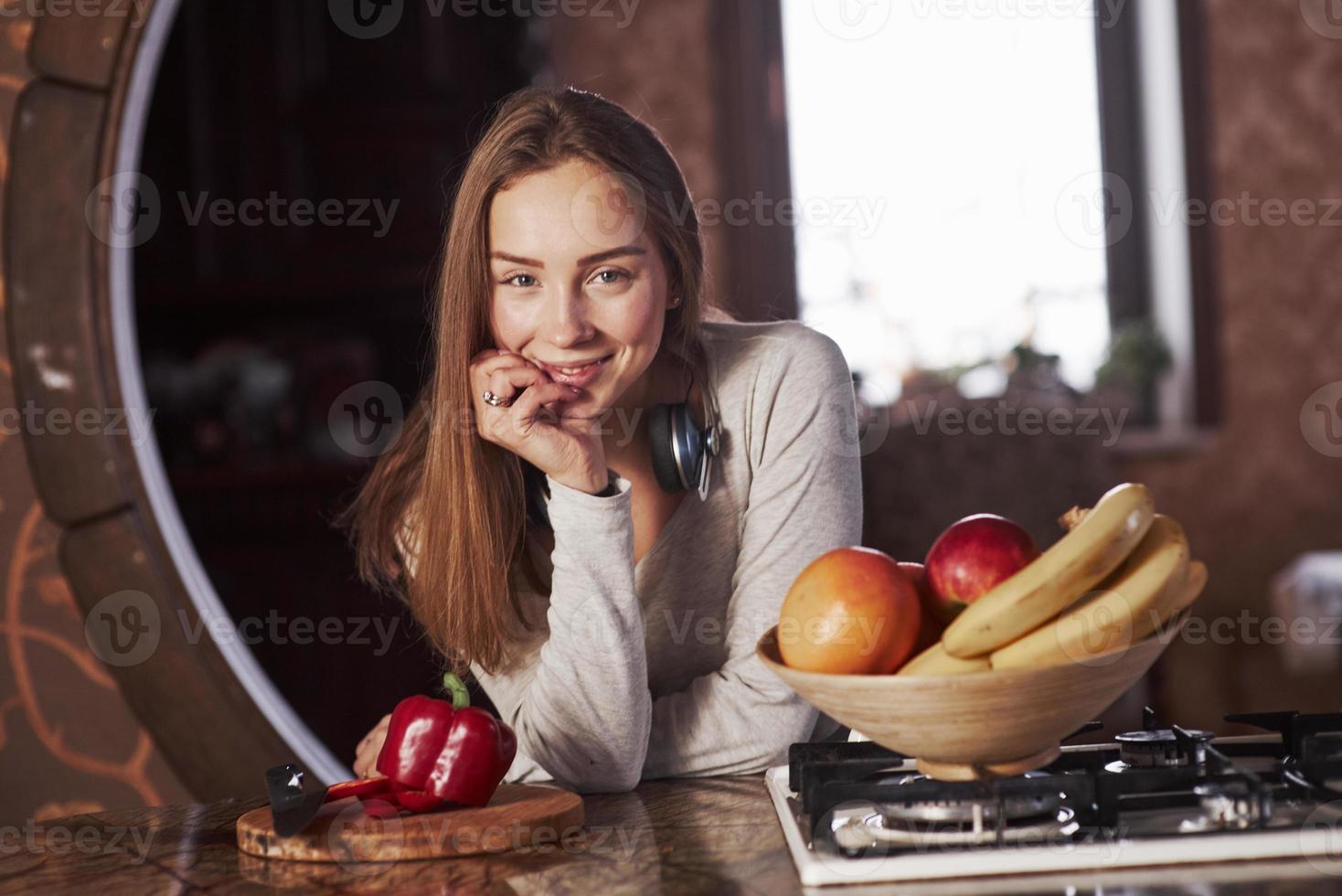 söt och vacker. ganska ung kvinna som står i det moderna köket nära gasspis foto