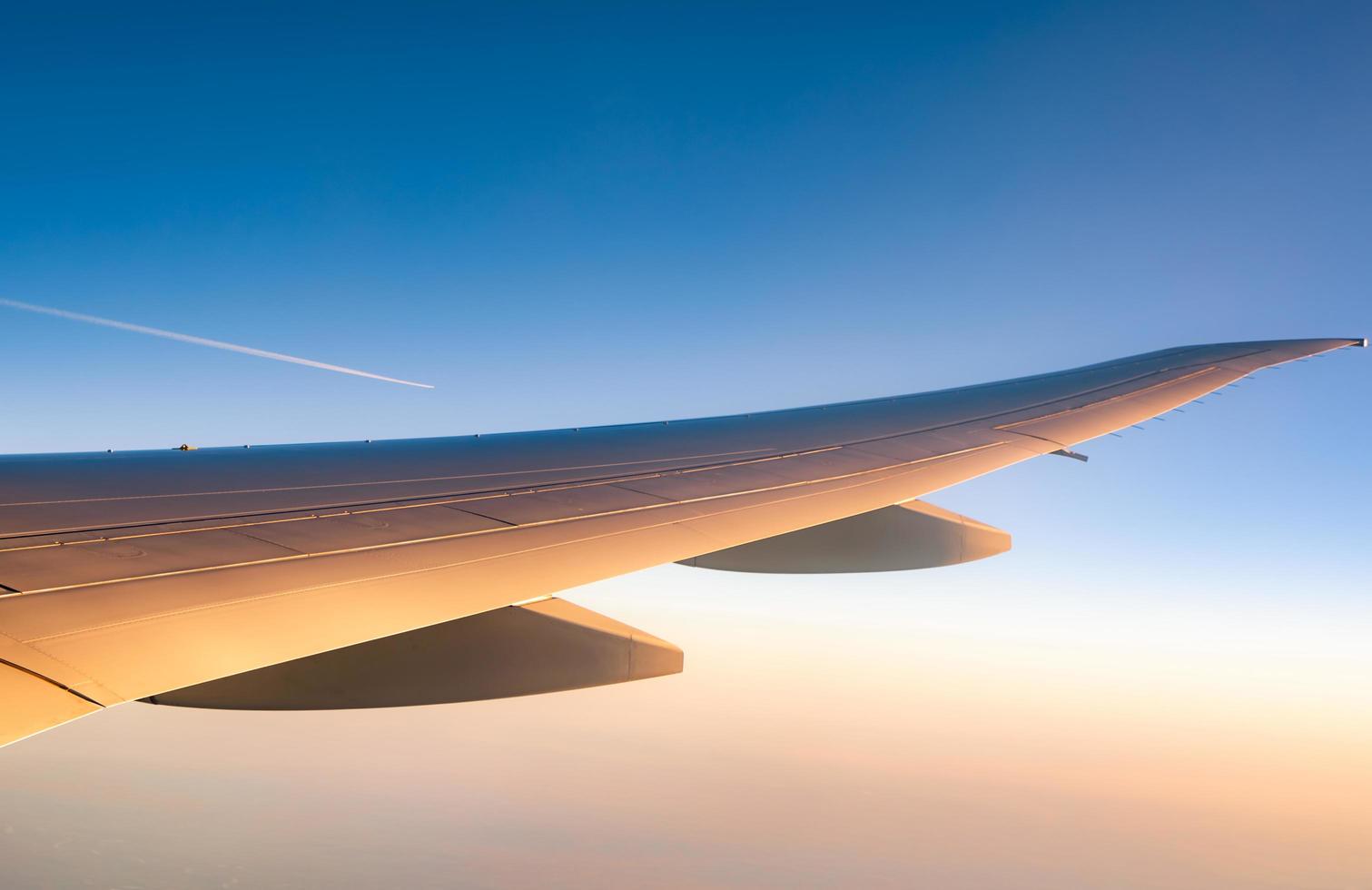 flygplansvingen över staden. flygplan som flyger på blå himmel. naturskön utsikt från flygplansfönstret. kommersiellt flygbolag flyg på morgonen med solljus. plan vinge ovanför molnen. flygmekanik koncept. foto